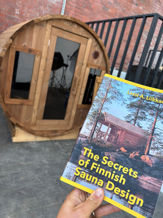 Immerse Barrel sauna with Finish sauna design book in front of it